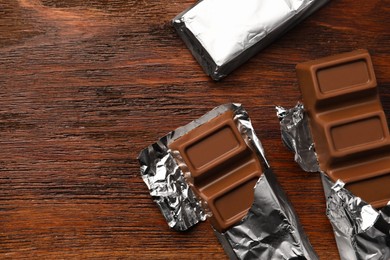 Tasty chocolate bars on wooden table, flat lay. Space for text