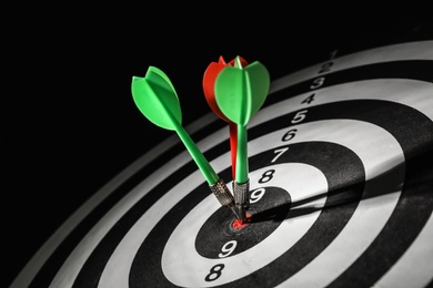 Photo of Arrows hitting target on dart board against black background