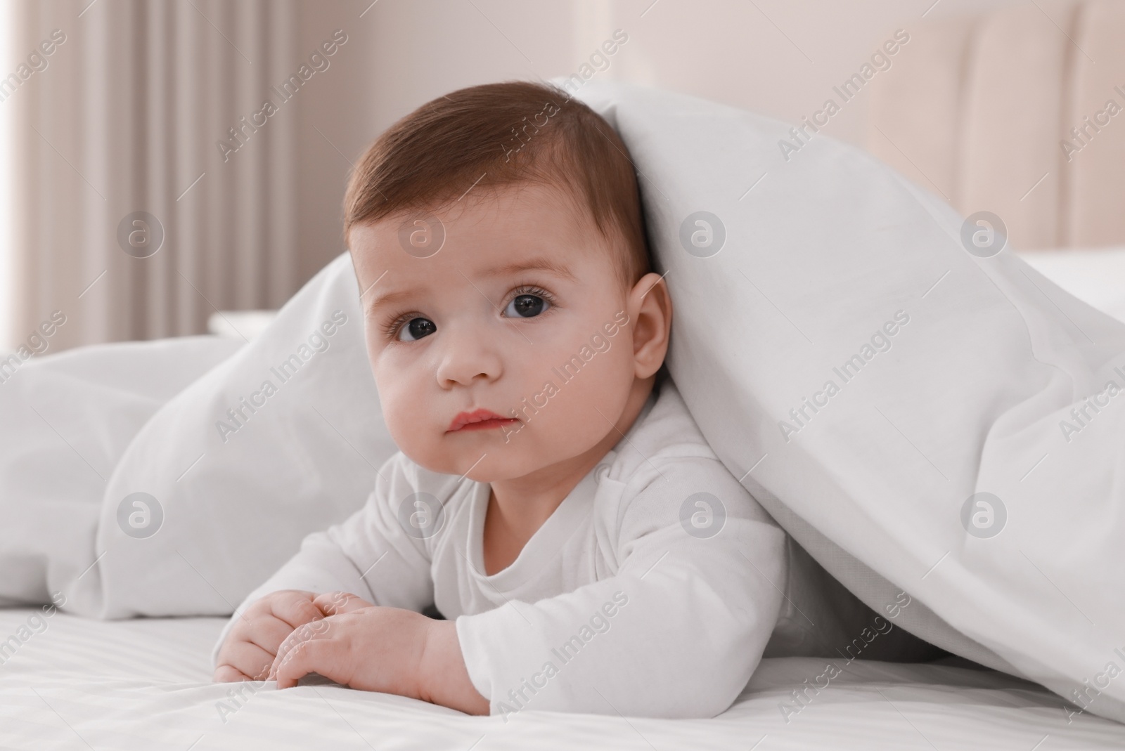 Photo of Cute little baby in bed under soft blanket indoors