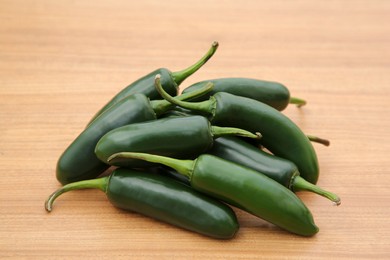 Photo of Pile of fresh ripe green jalapeno peppers on wooden table