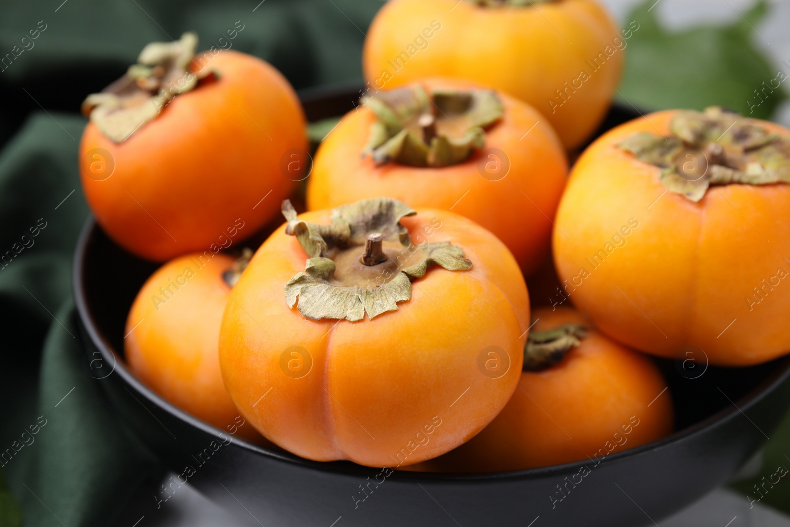 Photo of Bowl with delicious ripe juicy persimmons, closeup