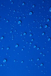 Water drops on blue background, top view