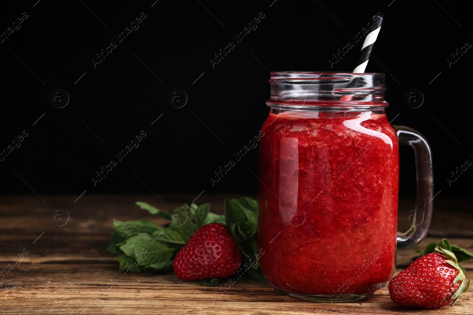 Photo of Tasty strawberry smoothie and mint on wooden table