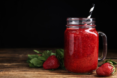 Photo of Tasty strawberry smoothie and mint on wooden table