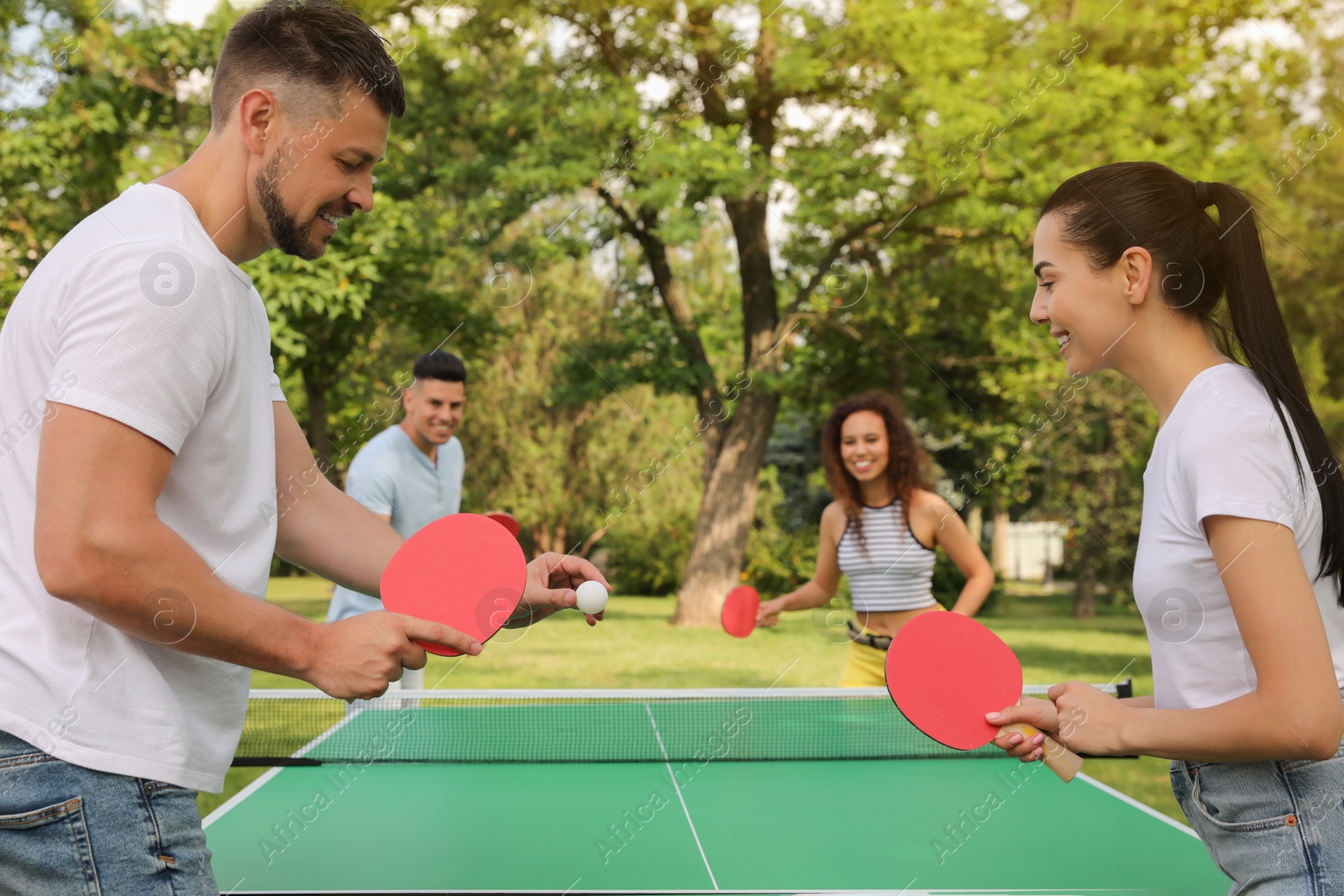 Photo of Friends playing ping pong outdoors on summer day