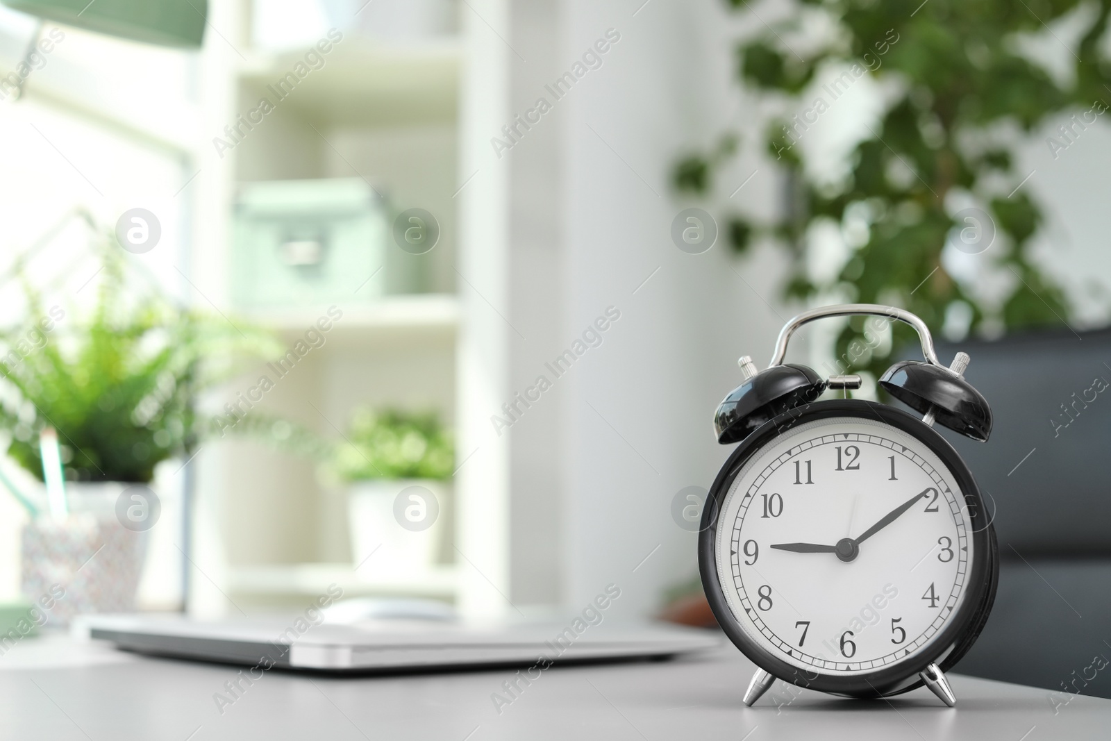 Photo of Alarm clock on table in office. Time to work