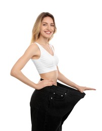 Photo of Young woman wearing big jeans after weight loss on white background