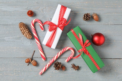 Photo of Flat lay composition with Christmas gift boxes and candy canes on grey wooden table