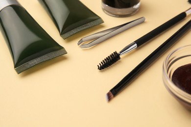 Photo of Eyebrow henna and tools on beige background, closeup