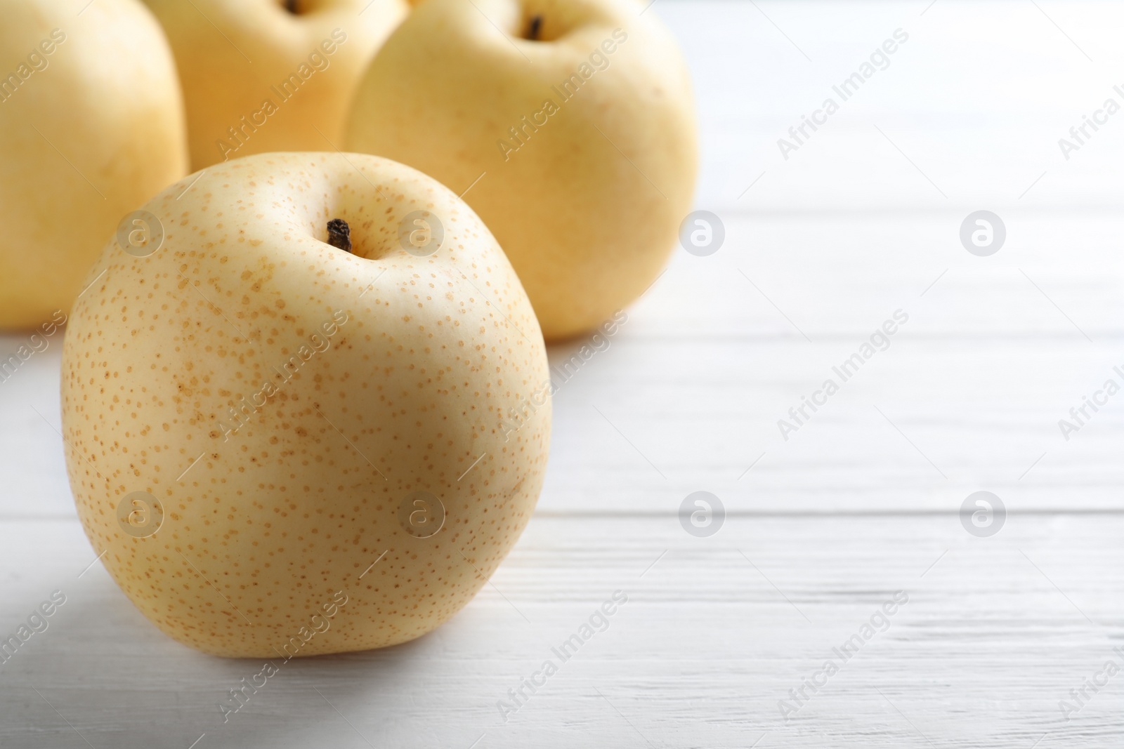Photo of Ripe apple pear on white wooden table. Space for text