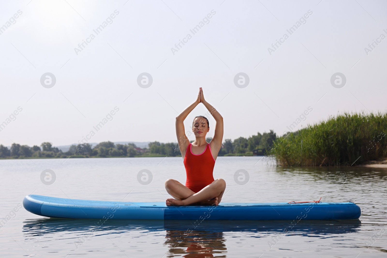 Photo of Woman practicing yoga on light blue SUP board on river