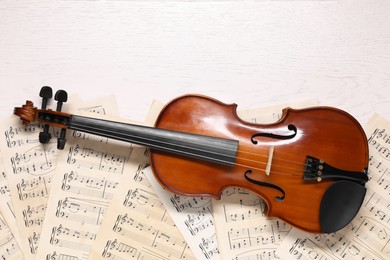 Photo of Violin and music sheets on white wooden table, top view. Space for text