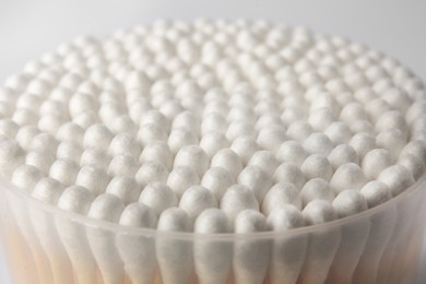 Open container with cotton buds on white background, closeup