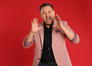 Portrait of screaming mature man on red background