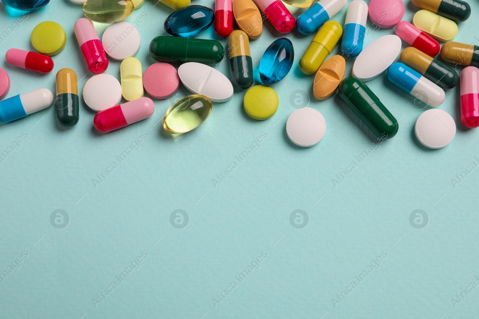 Photo of Many different pills on light turquoise background, flat lay. Space for text