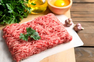 Photo of Raw ground meat, parsley and garlic on wooden table