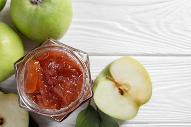 Glass jar of delicious apple jam and fresh fruits on white wooden table, flat lay. Space for text