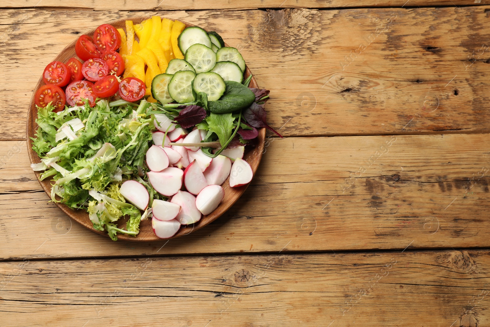 Photo of Vegetarian diet. Plate with tasty vegetables on wooden table, top view. Space for text