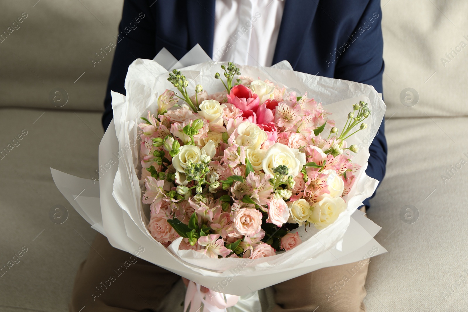 Photo of Man with beautiful bouquet of flowers on sofa indoors, closeup