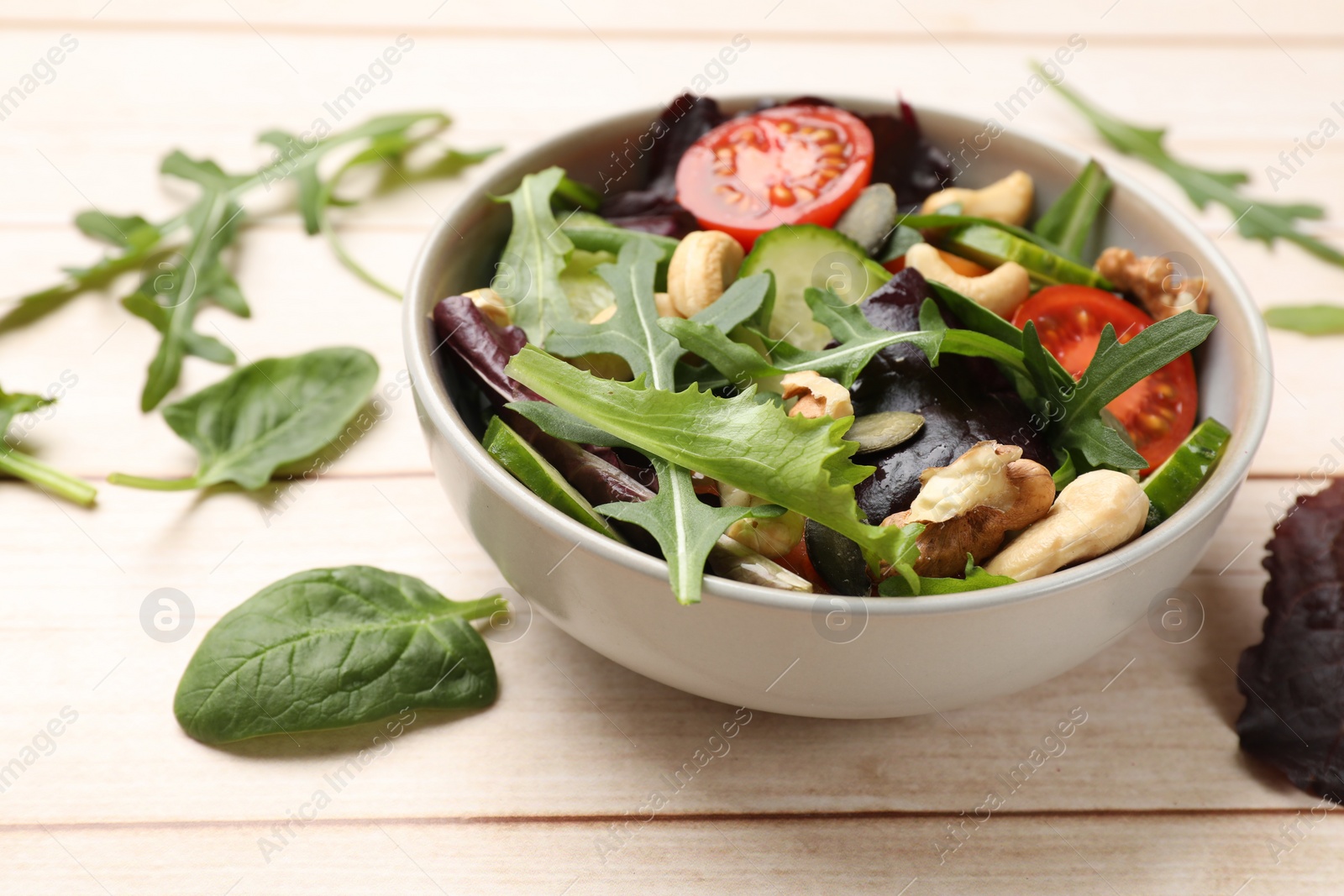 Photo of Tasty fresh vegetarian salad on light wooden table, closeup