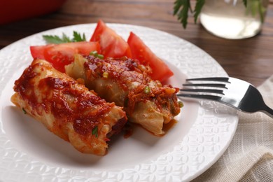 Delicious stuffed cabbage rolls with tomatoes served on table, closeup