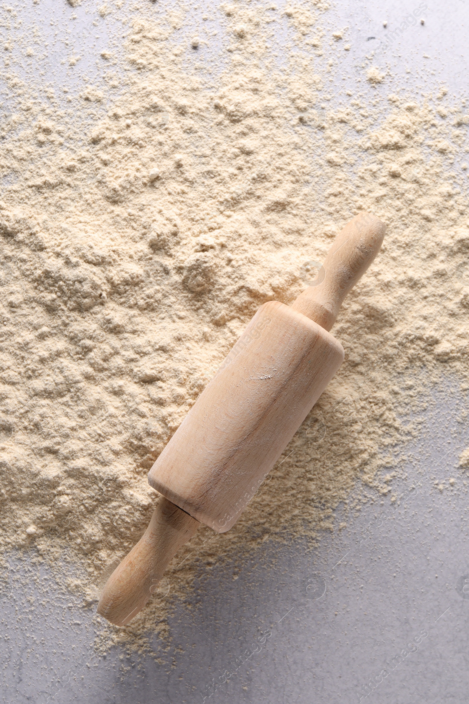 Photo of Pile of flour and rolling pin on light textured table, top view