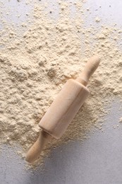 Photo of Pile of flour and rolling pin on light textured table, top view