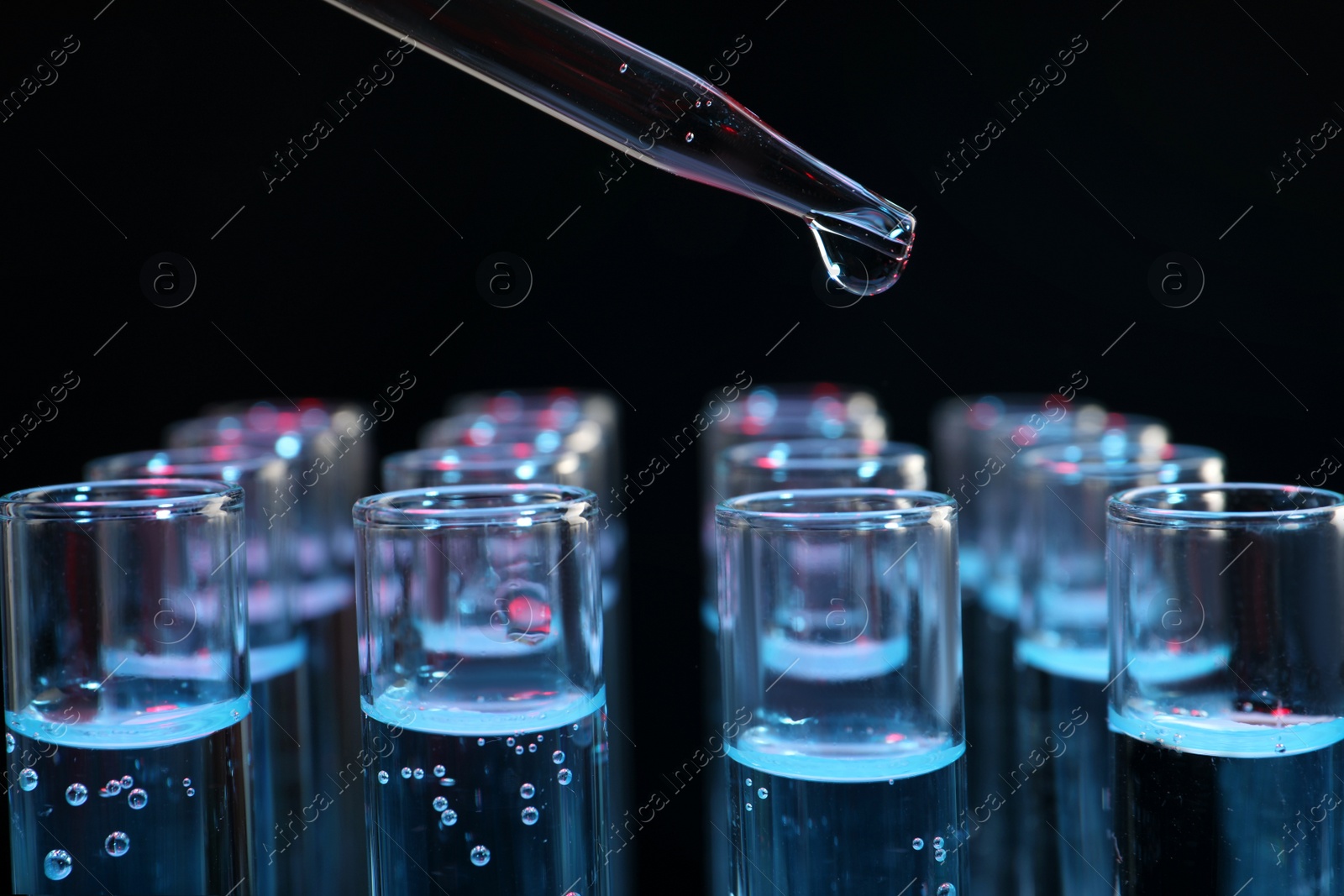 Photo of Dripping reagent into test tube on black background, closeup. Laboratory analysis