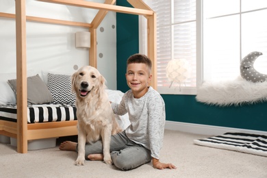 Photo of Little boy with his dog in stylish bedroom interior