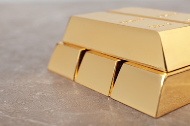 Photo of Stacked shiny gold bars on color table, closeup