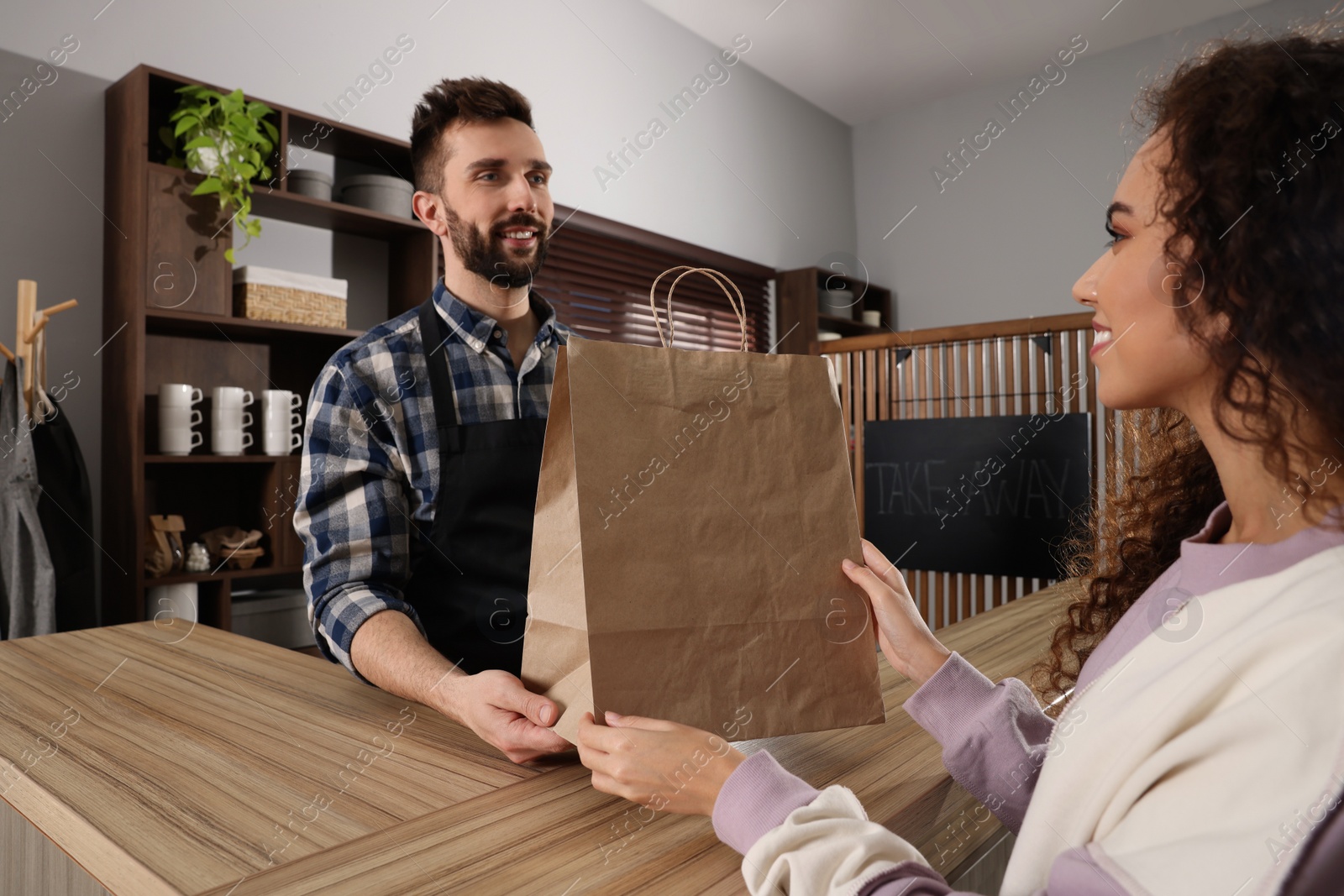 Photo of Worker giving paper bag to customer in cafe