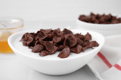 Photo of Breakfast cereal. Chocolate corn flakes and milk in bowl on white table, closeup