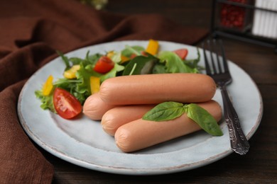 Photo of Delicious boiled sausages with salad on wooden table, closeup