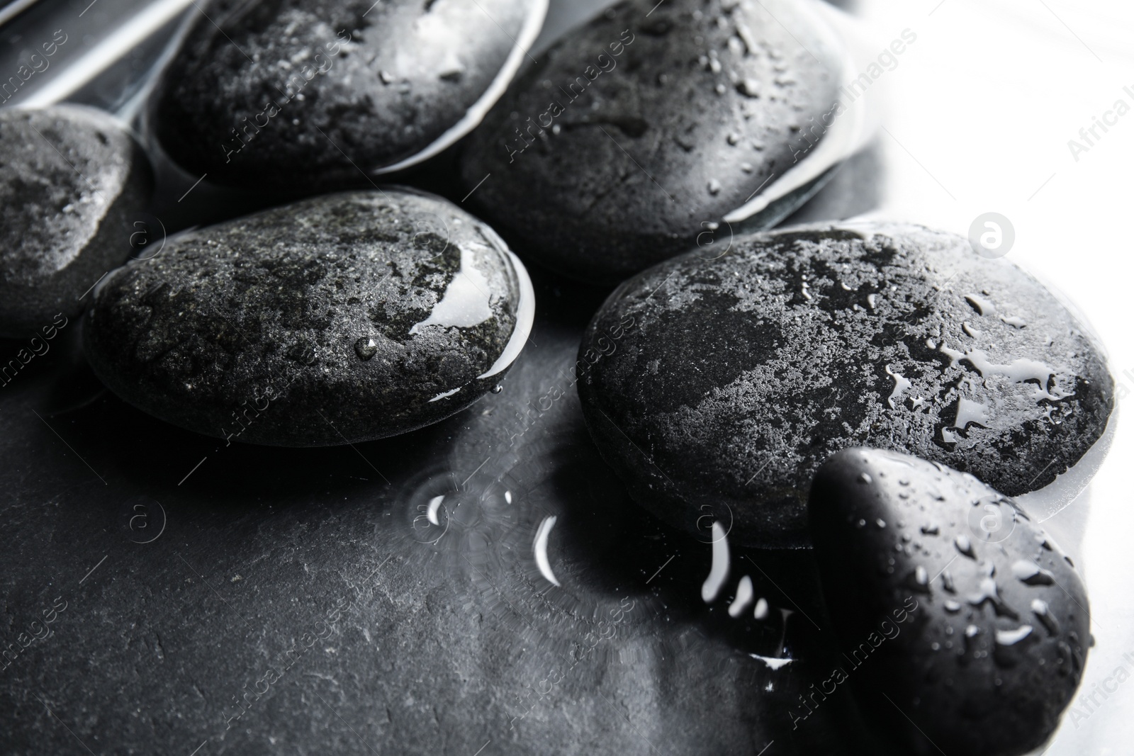 Photo of Stones in water on dark background, closeup. Zen lifestyle