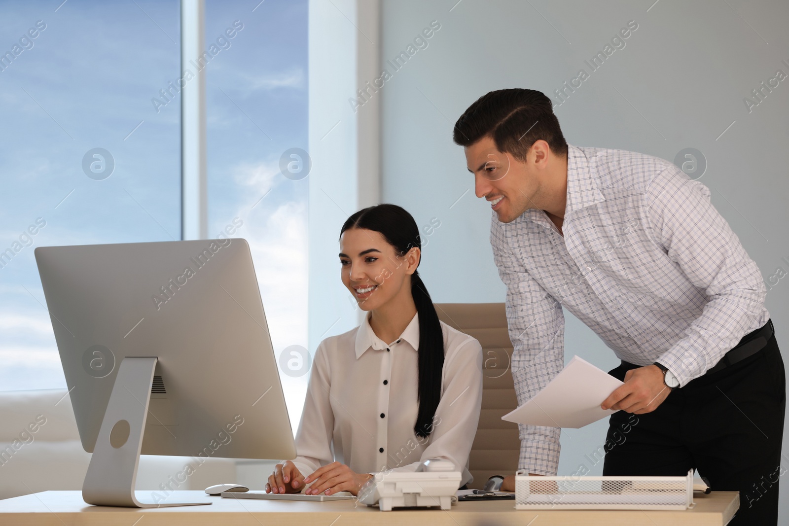 Photo of Secretary and her boss working at table in office