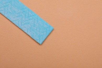 One stick of chewing gum on coral background, top view. Space for text