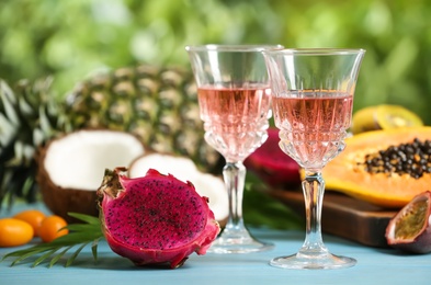 Photo of Delicious exotic fruits and wine on light blue wooden table