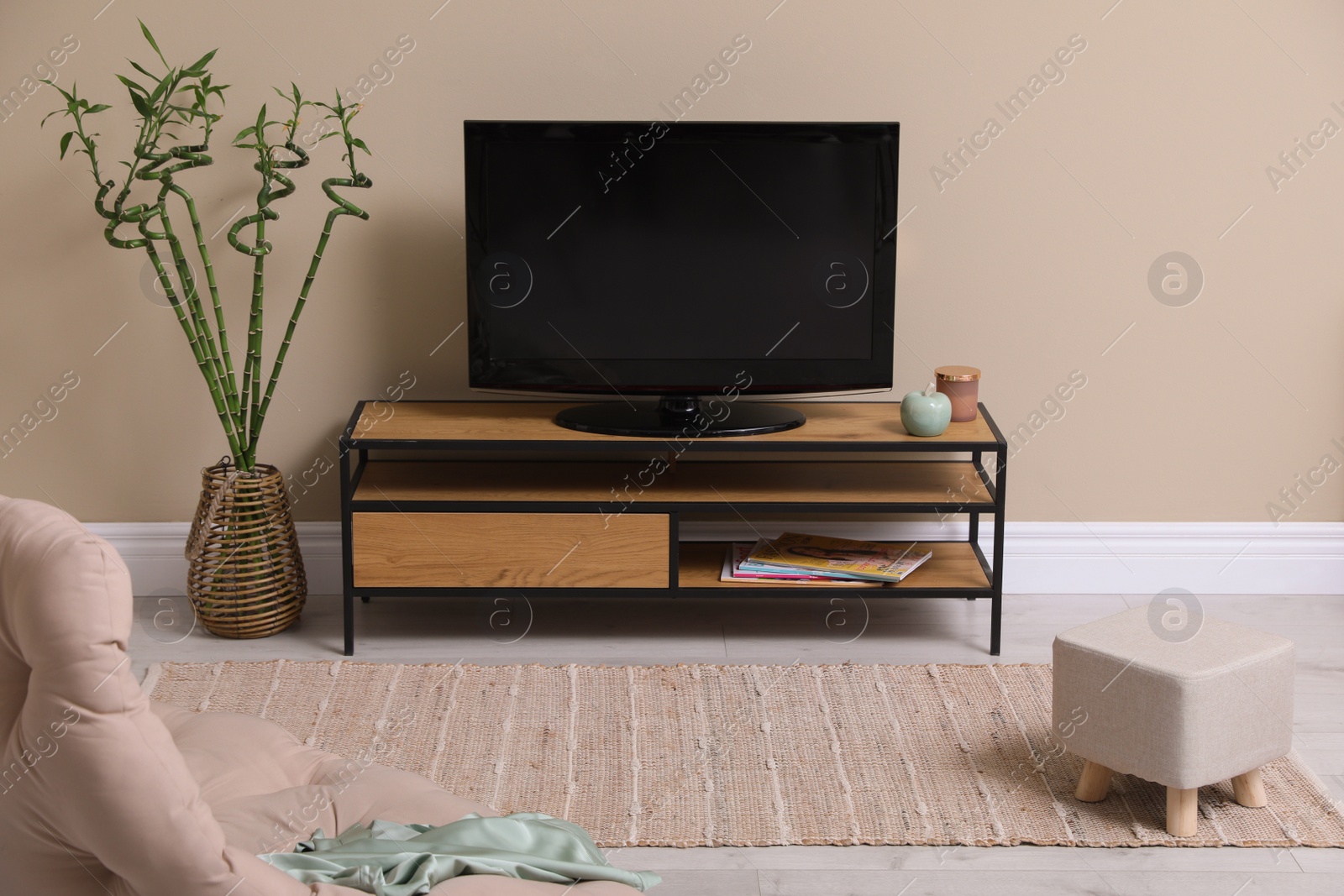 Photo of Stylish living room interior with beige rug, comfortable chair and TV set