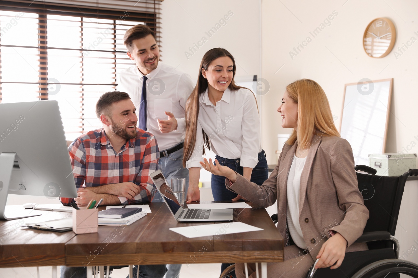 Photo of Woman in wheelchair with her colleagues at workplace