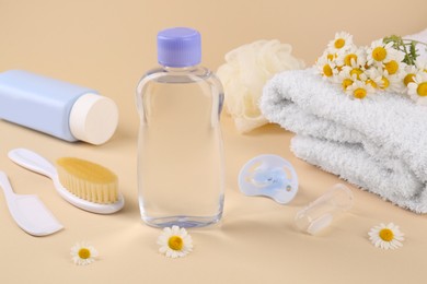 Photo of Bottle with baby oil, flowers and accessories on beige background