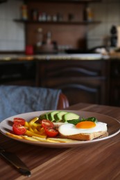 Tasty toasts with fried egg, avocado, cheese and vegetables on wooden table, closeup