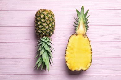 Photo of Fresh whole and cut pineapples on pink wooden background, top view