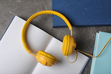 Modern headphones with hardcover books on grey background, top view