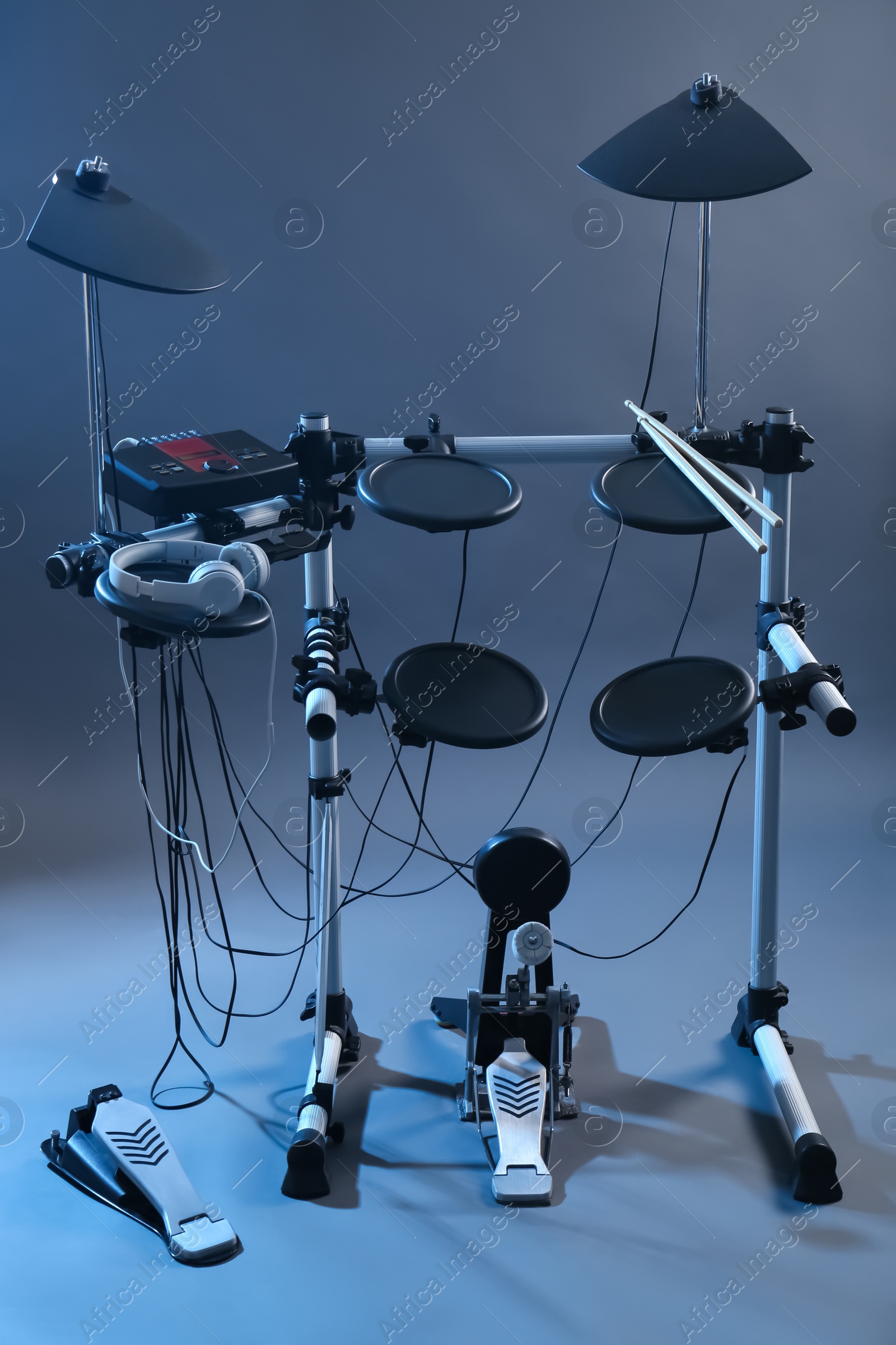 Photo of Modern electronic drum kit on grey background, toned in blue. Musical instrument