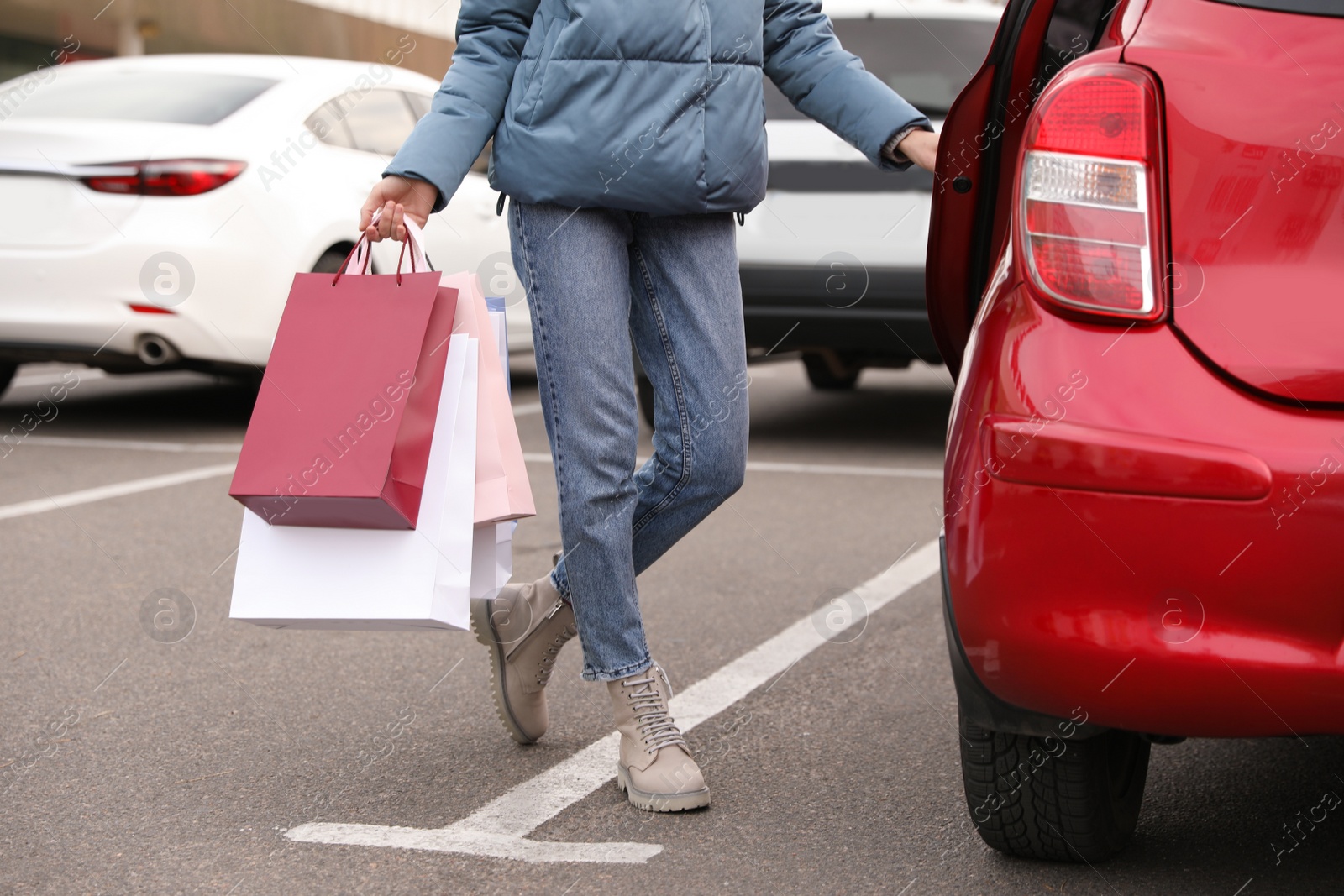 Photo of Woman with shopping bags near her car outdoors, closeup