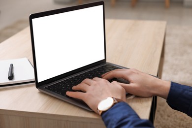 Photo of Man working on laptop at wooden desk indoors, closeup
