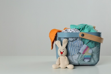 Photo of Laundry basket with different children's clothes and toy on light background. Space for text