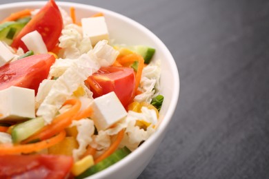 Photo of Tasty salad with Chinese cabbage, carrot, cheese, cucumber, corn and tomato on black table, closeup. Space for text