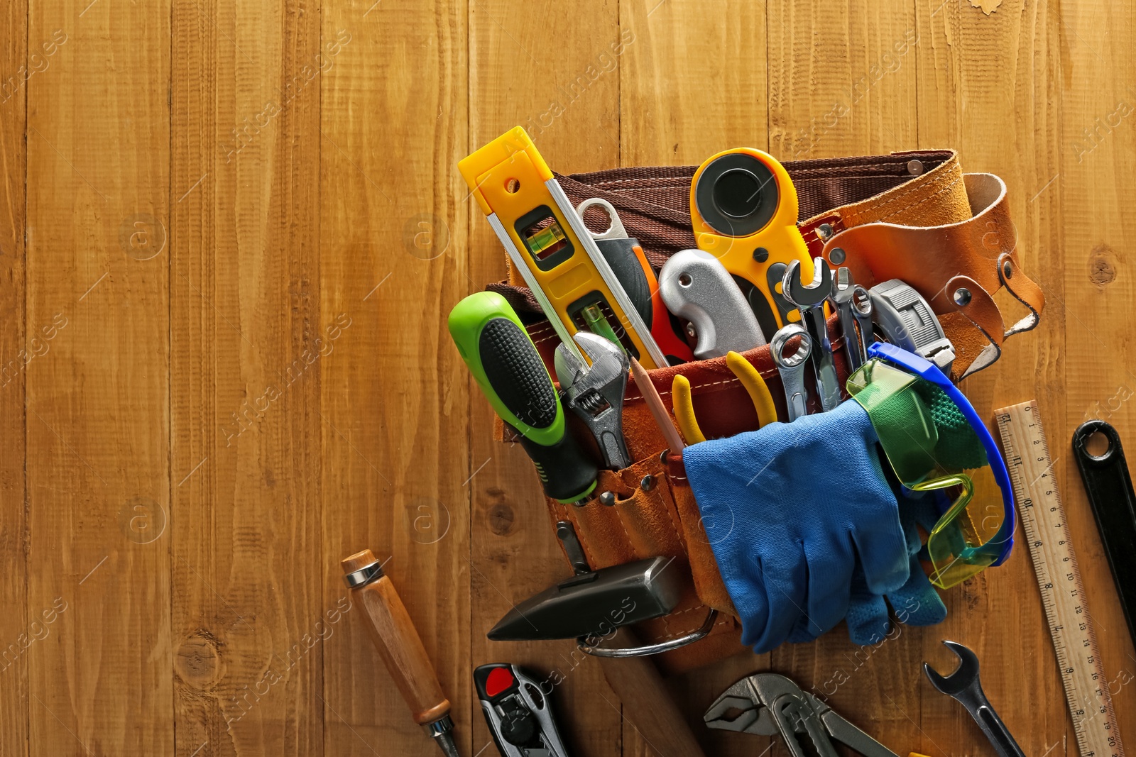 Photo of Belt with different tools on wooden table, top view. Space for text