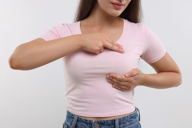Photo of Woman doing breast self-examination on white background, closeup